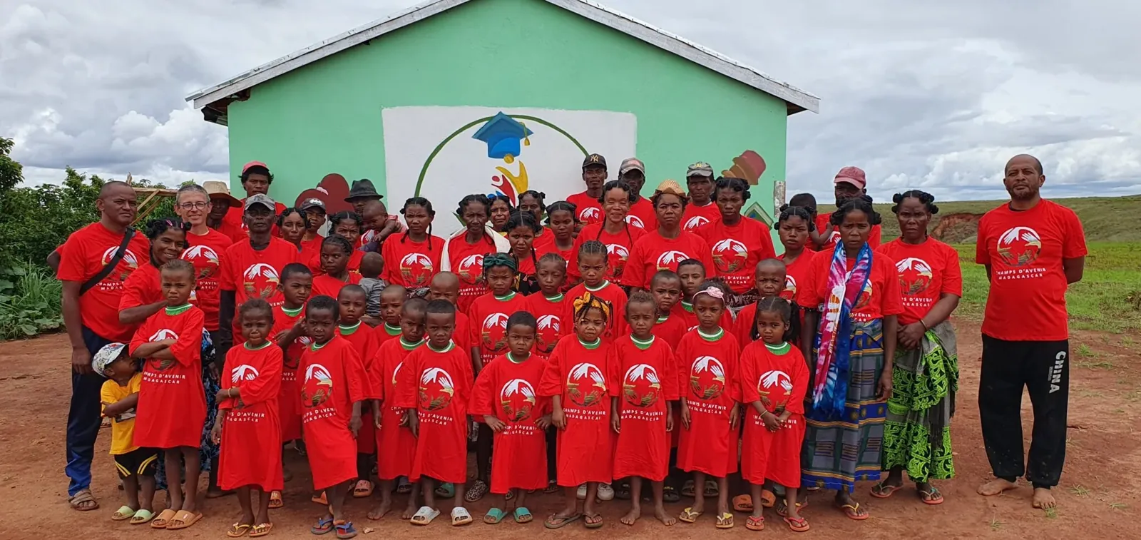 Les enfants et l’équipe réunis devant l’école, en tee-shirts rouges